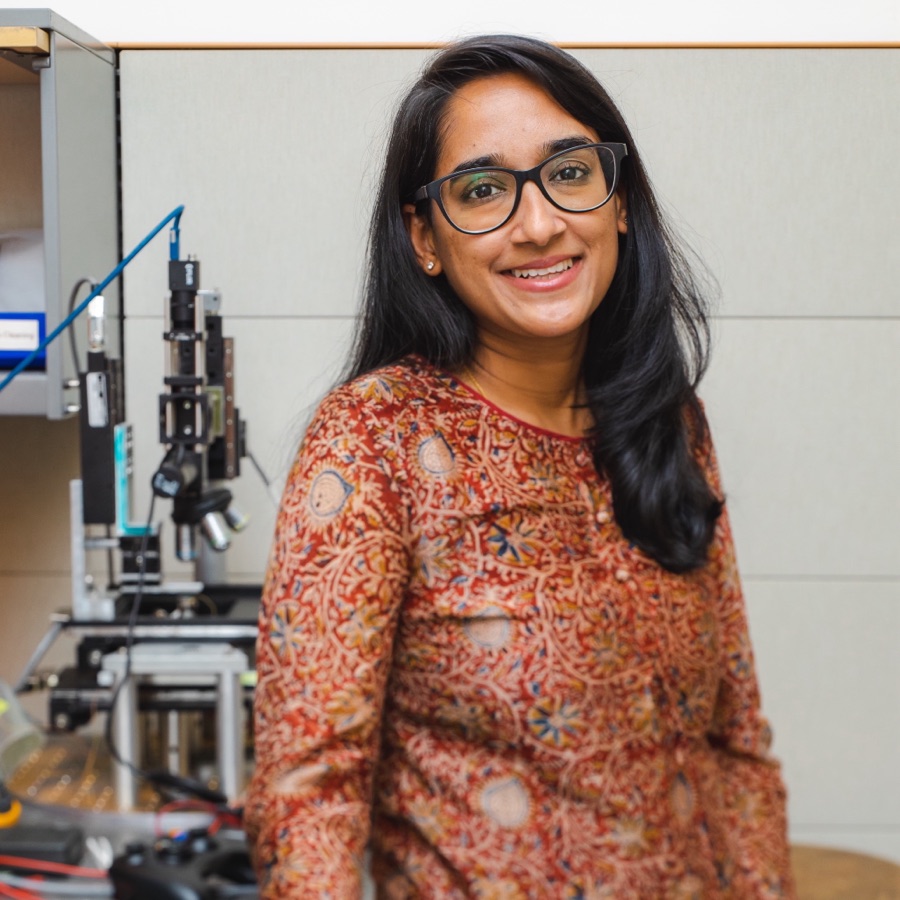 Archana Raja in the lab beside an optical microscope